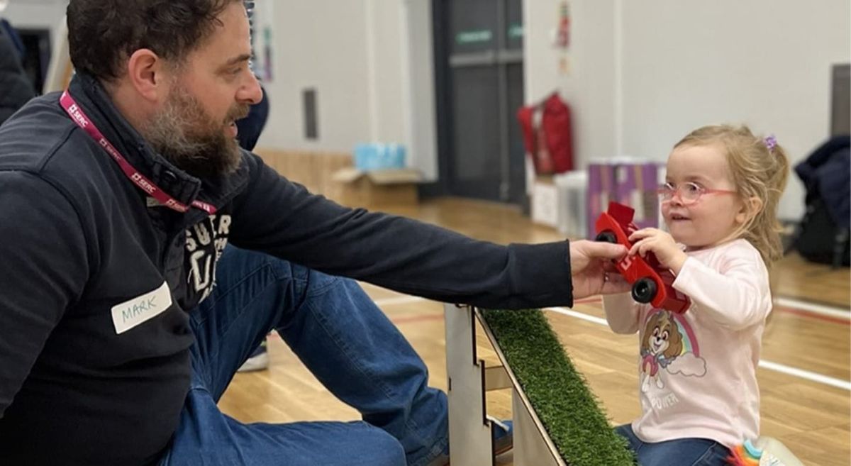 Man and small child holding a small toy car.